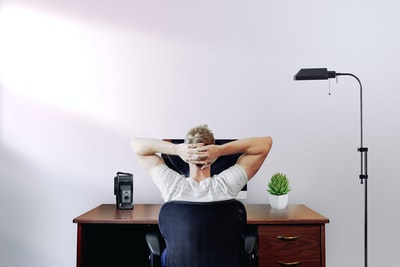 男人抱着他的头坐在椅子靠近电脑桌
